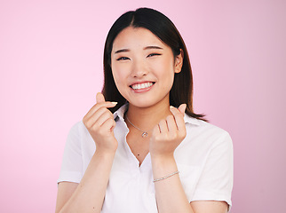 Image showing Happy asian woman, portrait and love hands, sign or gesture in romance against a pink studio background. Face of female person smile in happiness with loving emoji or symbol for valentines day