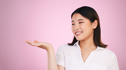 Image showing Happy asian woman, palm and advertising on mockup space in marketing against a pink studio background. Female person with hands out in market show, presentation or product advertisement on mock up