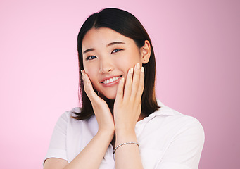 Image showing Beauty, smile and hands on woman face in studio for self love, promotion and care on pink background. Happy, portrait and confident Japanese female model with acceptance, satisfaction and positivity