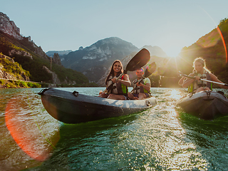 Image showing A group of friends enjoying fun and kayaking exploring the calm river, surrounding forest and large natural river canyons during an idyllic sunset.