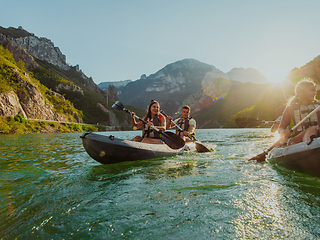 Image showing A group of friends enjoying fun and kayaking exploring the calm river, surrounding forest and large natural river canyons during an idyllic sunset.