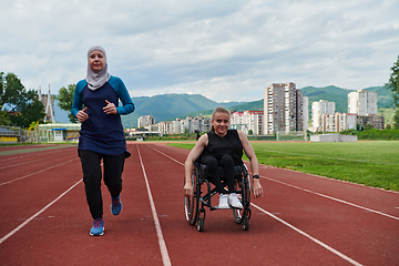 Image showing A Muslim woman in a burqa running together with a woman in a wheelchair on the marathon course, preparing for future competitions.