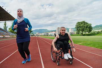 Image showing A Muslim woman in a burqa running together with a woman in a wheelchair on the marathon course, preparing for future competitions.