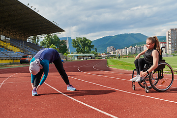 Image showing Two strong and inspiring women, one a Muslim wearing a burka and the other in a wheelchair stretching and preparing their bodies for a marathon race on the track