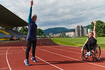 Image showing Two strong and inspiring women, one a Muslim wearing a burka and the other in a wheelchair stretching and preparing their bodies for a marathon race on the track