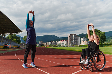 Image showing Two strong and inspiring women, one a Muslim wearing a burka and the other in a wheelchair stretching and preparing their bodies for a marathon race on the track