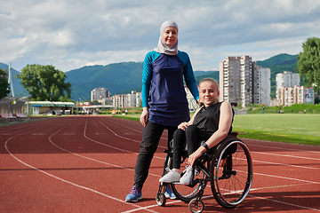 Image showing A Muslim woman wearing a burqa resting with a woman with disability after a hard training session on the marathon course