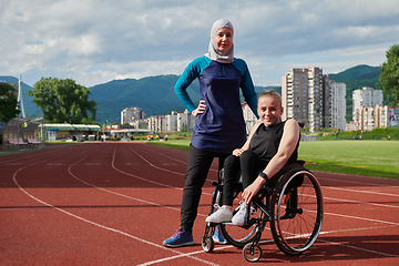 Image showing A Muslim woman wearing a burqa resting with a woman with disability after a hard training session on the marathon course