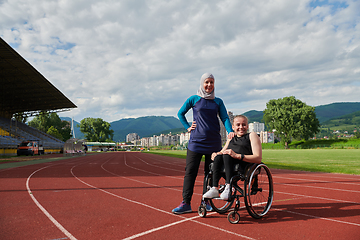 Image showing A Muslim woman wearing a burqa resting with a woman with disability after a hard training session on the marathon course