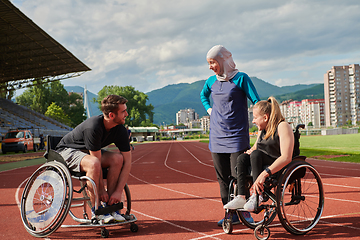 Image showing A woman with a disability in a wheelchair talking after training with a woman wearing a hijab and a man in a wheelchair