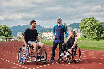 Image showing A woman with a disability in a wheelchair talking after training with a woman wearing a hijab and a man in a wheelchair