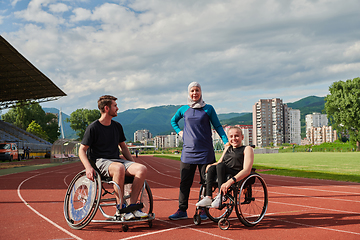 Image showing A woman with a disability in a wheelchair talking after training with a woman wearing a hijab and a man in a wheelchair