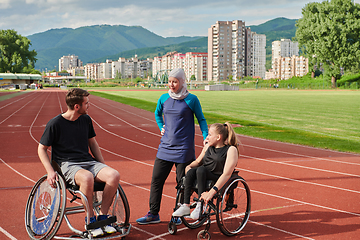 Image showing A woman with a disability in a wheelchair talking after training with a woman wearing a hijab and a man in a wheelchair