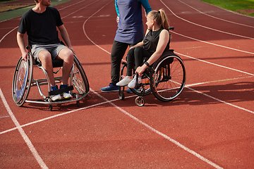 Image showing A woman with a disability in a wheelchair talking after training with a woman wearing a hijab and a man in a wheelchair