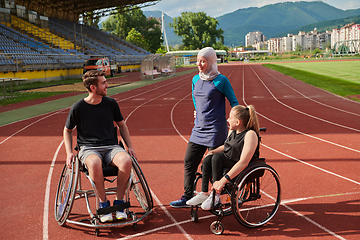 Image showing A woman with a disability in a wheelchair talking after training with a woman wearing a hijab and a man in a wheelchair