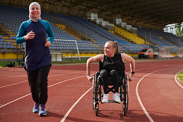 Image showing A Muslim woman in a burqa running together with a woman in a wheelchair on the marathon course, preparing for future competitions.