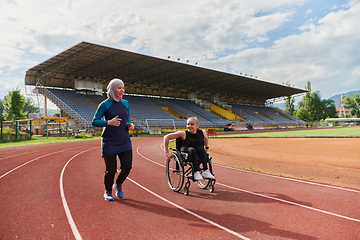 Image showing A Muslim woman in a burqa running together with a woman in a wheelchair on the marathon course, preparing for future competitions.