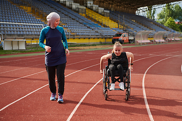 Image showing A Muslim woman in a burqa running together with a woman in a wheelchair on the marathon course, preparing for future competitions.