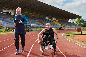 Image showing A Muslim woman in a burqa running together with a woman in a wheelchair on the marathon course, preparing for future competitions.