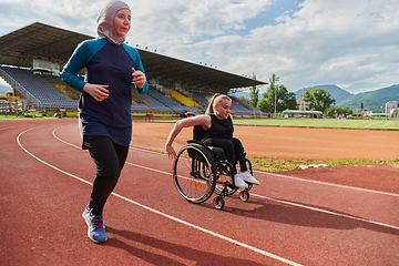 Image showing A Muslim woman in a burqa running together with a woman in a wheelchair on the marathon course, preparing for future competitions.