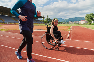 Image showing A Muslim woman in a burqa running together with a woman in a wheelchair on the marathon course, preparing for future competitions.