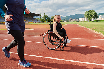 Image showing A Muslim woman in a burqa running together with a woman in a wheelchair on the marathon course, preparing for future competitions.