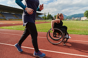 Image showing A Muslim woman in a burqa running together with a woman in a wheelchair on the marathon course, preparing for future competitions.