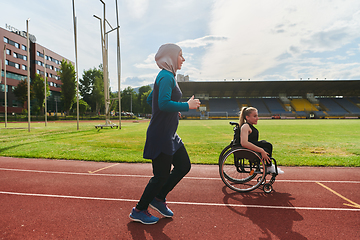 Image showing A Muslim woman in a burqa running together with a woman in a wheelchair on the marathon course, preparing for future competitions.