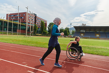 Image showing A Muslim woman in a burqa running together with a woman in a wheelchair on the marathon course, preparing for future competitions.