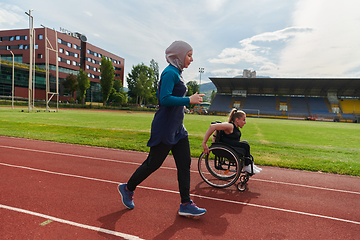 Image showing A Muslim woman in a burqa running together with a woman in a wheelchair on the marathon course, preparing for future competitions.