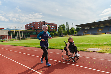 Image showing A Muslim woman in a burqa running together with a woman in a wheelchair on the marathon course, preparing for future competitions.