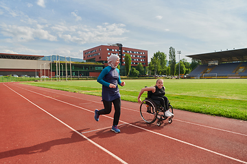 Image showing A Muslim woman in a burqa running together with a woman in a wheelchair on the marathon course, preparing for future competitions.