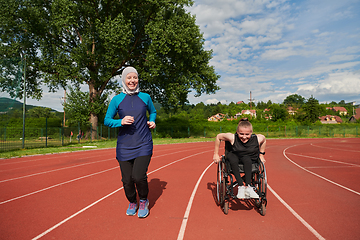 Image showing A Muslim woman in a burqa running together with a woman in a wheelchair on the marathon course, preparing for future competitions.