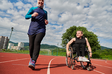 Image showing A Muslim woman in a burqa running together with a woman in a wheelchair on the marathon course, preparing for future competitions.