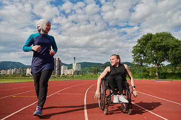 Image showing A Muslim woman in a burqa running together with a woman in a wheelchair on the marathon course, preparing for future competitions.