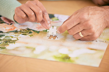 Image showing Puzzle on table, piece and hands of couple in home for bonding, fun activity and relax together. Retirement, marriage and closeup of people with jigsaw for playing games, hobby and entertainment