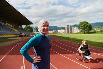 Image showing A Muslim woman wearing a burqa resting with a woman with disability after a hard training session on the marathon course