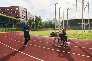 Image showing A Muslim woman in a burqa running together with a woman in a wheelchair on the marathon course, preparing for future competitions.