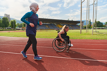 Image showing A Muslim woman in a burqa running together with a woman in a wheelchair on the marathon course, preparing for future competitions.