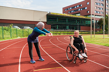 Image showing A Muslim woman in a burqa running together with a woman in a wheelchair on the marathon course, preparing for future competitions.