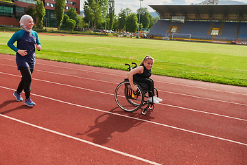 Image showing A Muslim woman in a burqa running together with a woman in a wheelchair on the marathon course, preparing for future competitions.