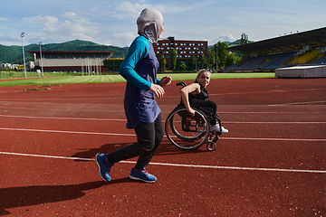 Image showing A Muslim woman in a burqa running together with a woman in a wheelchair on the marathon course, preparing for future competitions.