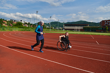 Image showing A Muslim woman in a burqa running together with a woman in a wheelchair on the marathon course, preparing for future competitions.