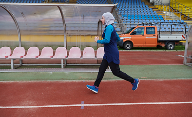 Image showing A muslim woman in a burqa sports muslim clothes running on a marathon course and preparing for upcoming competitions