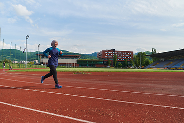 Image showing A muslim woman in a burqa sports muslim clothes running on a marathon course and preparing for upcoming competitions