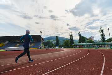 Image showing A muslim woman in a burqa sports muslim clothes running on a marathon course and preparing for upcoming competitions