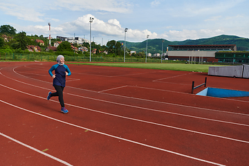 Image showing A muslim woman in a burqa sports muslim clothes running on a marathon course and preparing for upcoming competitions