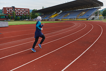 Image showing A muslim woman in a burqa sports muslim clothes running on a marathon course and preparing for upcoming competitions