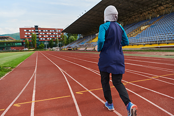 Image showing A muslim woman in a burqa sports muslim clothes running on a marathon course and preparing for upcoming competitions