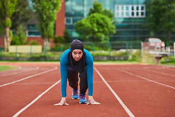 Image showing Muslim woman in burqa in sporty Muslim clothes in starting pose for running